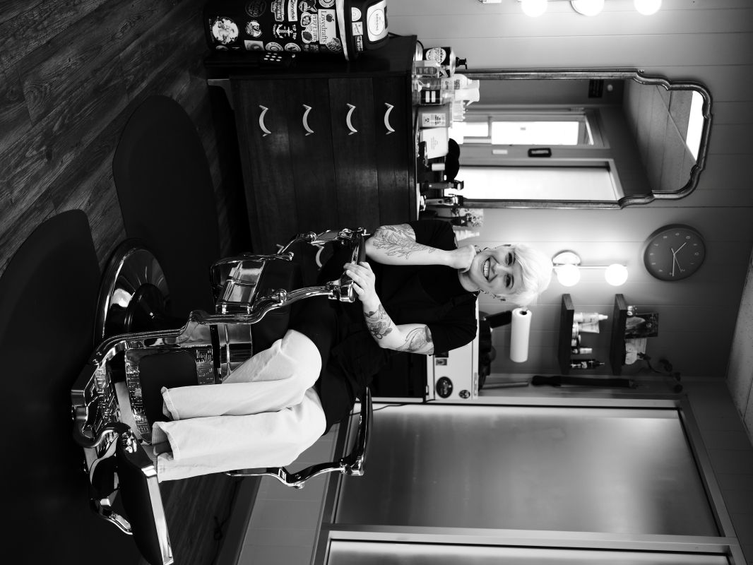 Hannah Stucky seated in the antique barber chair at The Charming Barber
