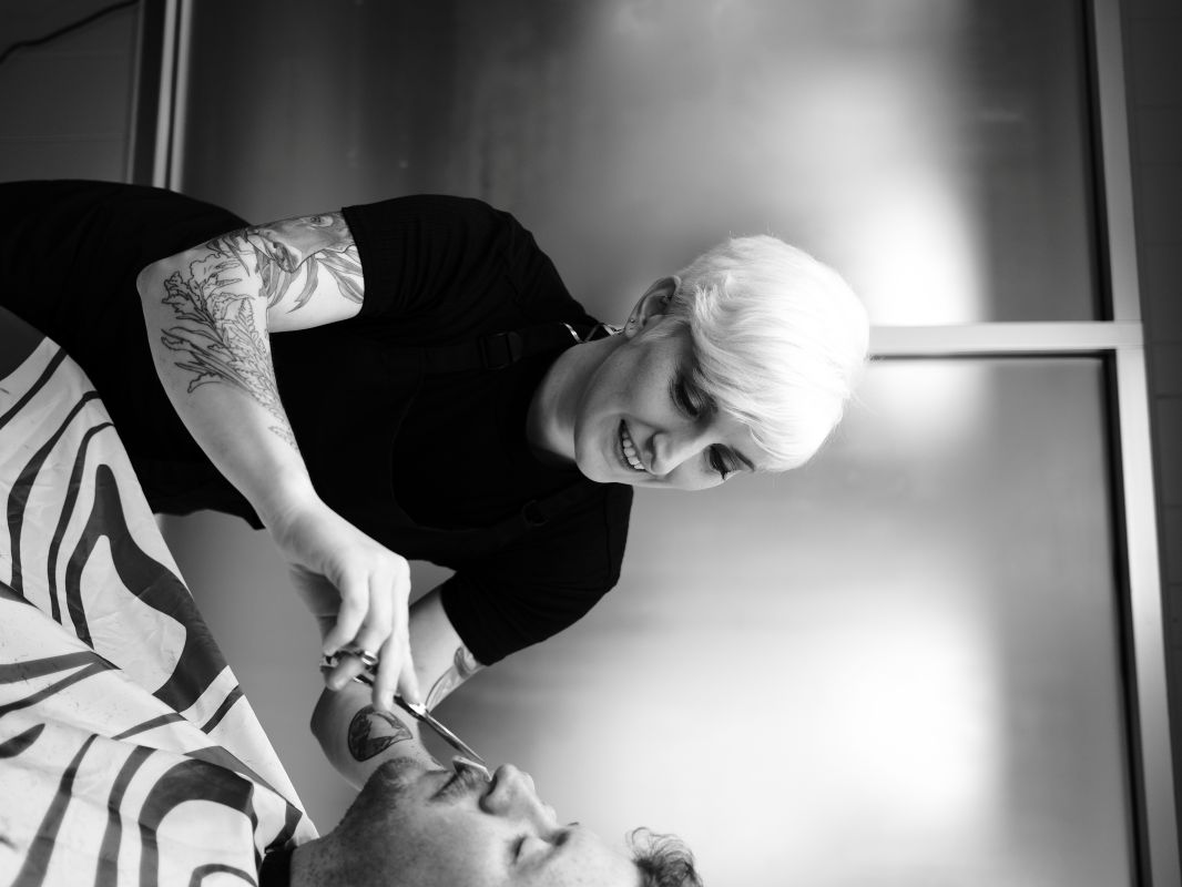 Hannah trimming a client's beard at The Charming Barber